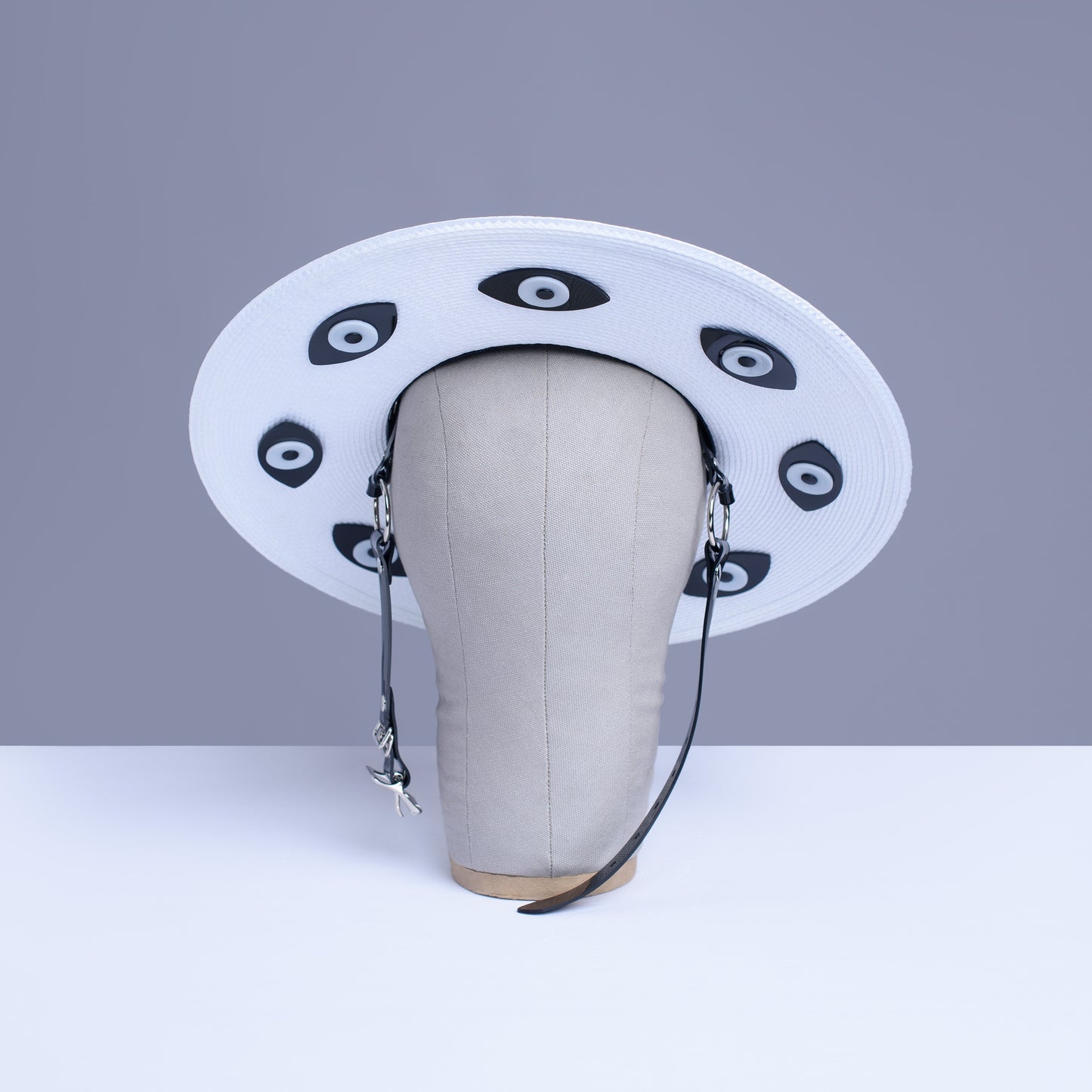 Apatico harness hat with wide brim. Black and white two-tone faux strap. Eyeball design all around the brim.